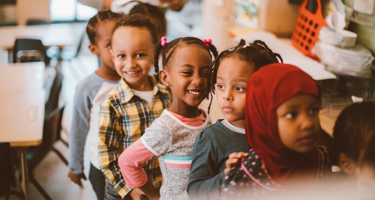 A row of smiling preschool children lined up in a Mile High Early Learning classroom.